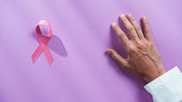 Dokter hand ad roze lint op de tafel