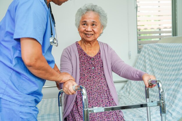 Dokter helpt Aziatische bejaarde vrouw met een handicap patiënt lopen met rollator in verpleegkundig ziekenhuis medisch concept