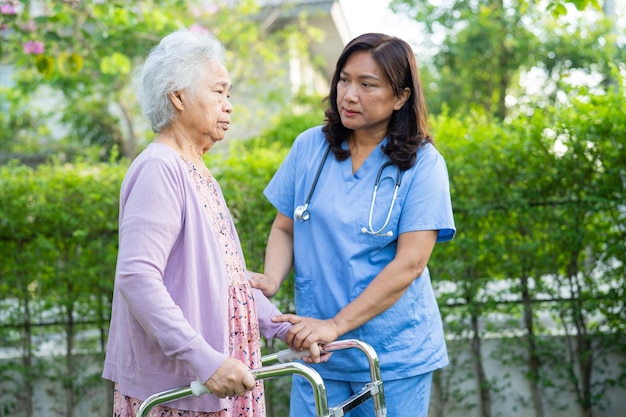 Dokter helpt en verzorgt Aziatische senioren of oudere oude damevrouwen gebruiken rollator met een sterke gezondheid tijdens het wandelen in het park in een fijne, frisse vakantie