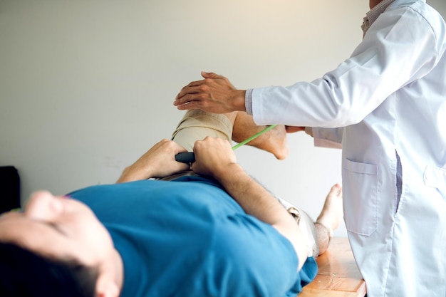 Foto dokter helpt patiënt bij het strekken van been in medische kliniek