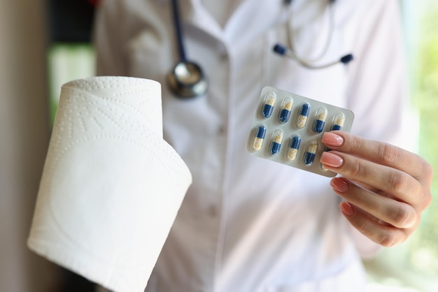 Dokter houdt een rol wc-papier en een pakje capsules close-up vrouwen medisch personeel