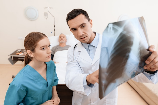 Dokter houdt een röntgenfoto vast, verpleegster staat naast hem.