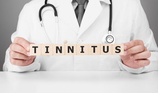 Dokter houdt houten kubussen in zijn handen met de tekst TINNITUS