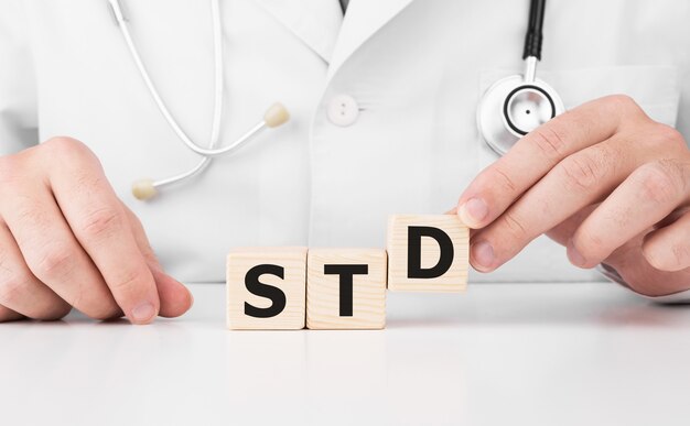 Dokter houdt houten kubussen in zijn handen met tekst STD