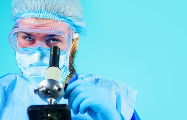 Dokter in beschermende maskerhandschoenen die monster onderzoeken met microscooponderzoek in laboratoriumclose-up