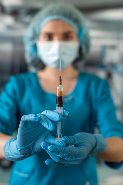 Dokter in blauw uniform met handschoen volledige virusbescherming met spuit met medicijnen