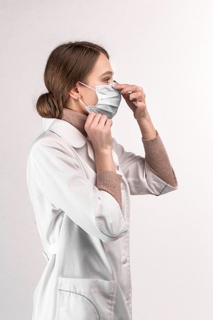 Dokter in een witte jas laat zien hoe je een medisch masker moet dragen