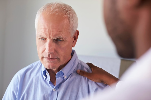 Foto dokter in gesprek met ongelukkige mannelijke patiënt in onderzoekskamer