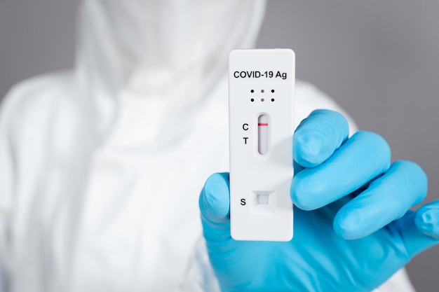 Foto dokter in pbm-pak met negatief testresultaat coronavirus (covid-19) met antigen rapid test kit (atk)