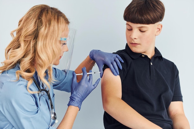 Dokter in uniform die vaccinatie maakt voor de jongen in zwart shirt