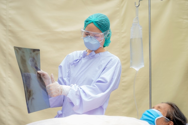 Dokter legt de resultaten van de longröntgenfoto uit aan een oudere patiënt die op het bed ligt
