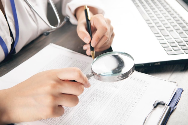 Dokter maakt aantekeningen op papieren en kijkt met een vergrootglas