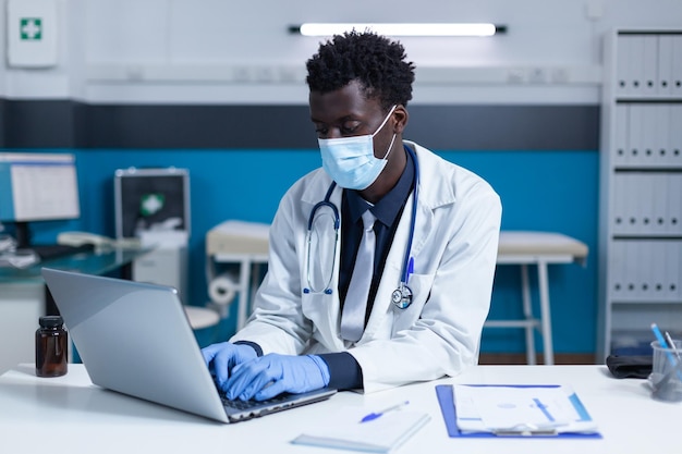 Dokter met een masker met een laptop in de kliniek