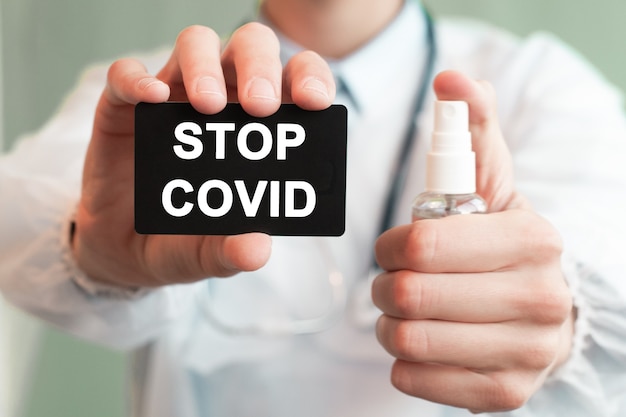 Dokter met een papieren zwarte kaart met tekst STOP COVID en de medicijnfles, medisch concept