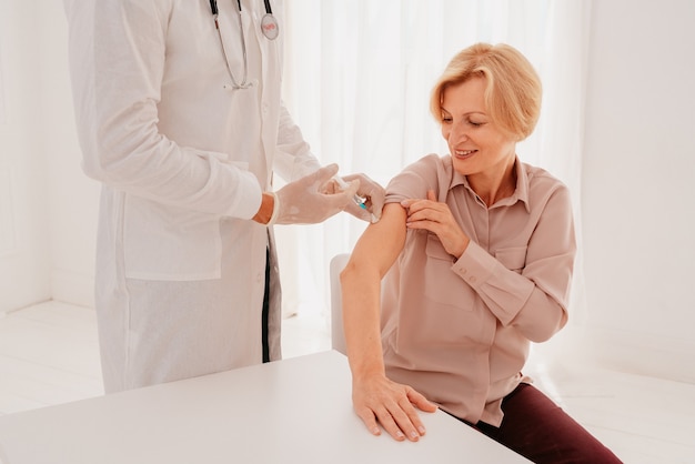 Dokter met masker en spuit staat klaar om het vaccin tegen covid toe te dienen