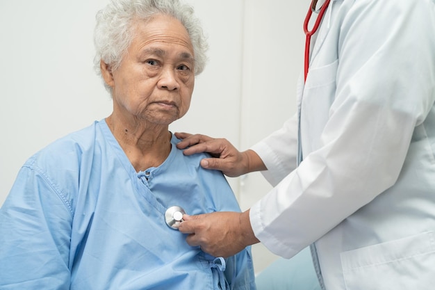 Foto dokter met stethoscoop die senior of oudere oude dame vrouw patiënt controleert zittend op een bed in de verpleegafdeling gezond sterk medisch concept