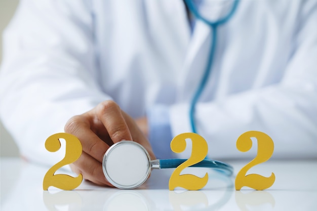 Dokter met stethoscoop in de buurt van gouden houten nummer 2022 Idee voor nieuwe trend in medische behandeling