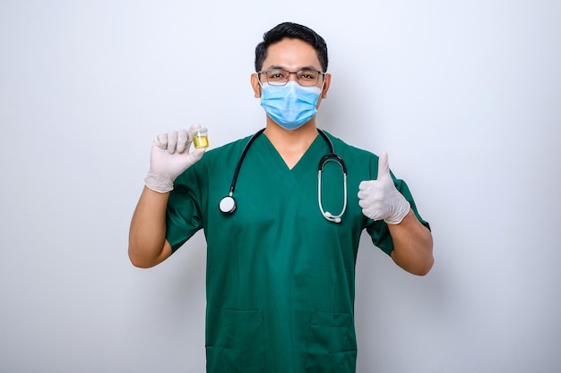 Dokter of medewerker van het klinieklaboratorium die urinemonster van de patiënt vasthoudt, draagt een medisch masker en handschoenen met duim omhoog