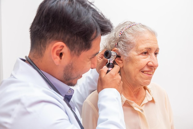 Foto dokter onderzoekt oor van oudere vrouw met otoscoop in kliniek