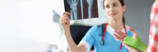 Dokter onderzoekt röntgenfoto van hand naast patiënt staat met verbonden hand