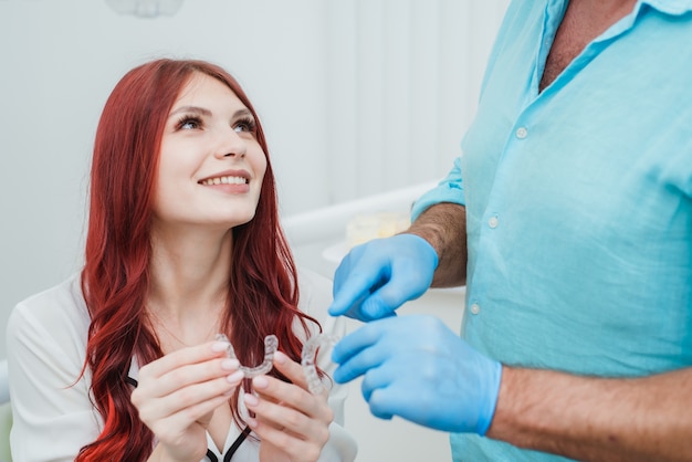 Dokter-orthodontist raadt een meisje siliconen aligners aan om tanden recht te zetten
