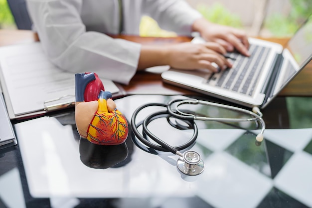 Foto dokter raadpleegt patiënt op laptop met anatomisch model van menselijk hart cardioloog ondersteunt het hart online doktersafspraak