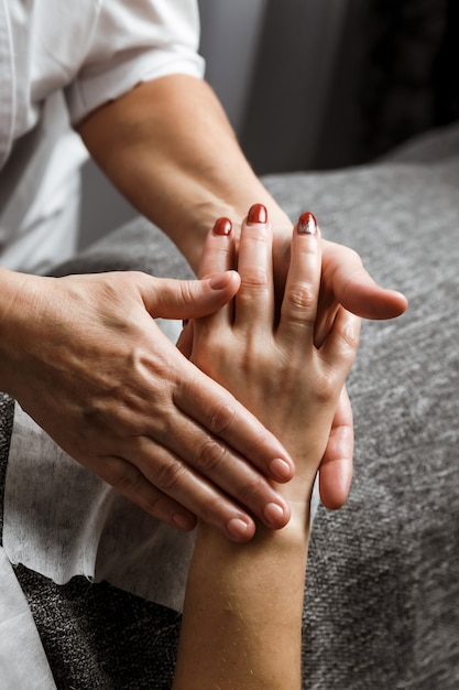 Dokter schoonheidsspecialist schoonheidsspecialiste masseert de handen van haar vrouwelijke cliënt