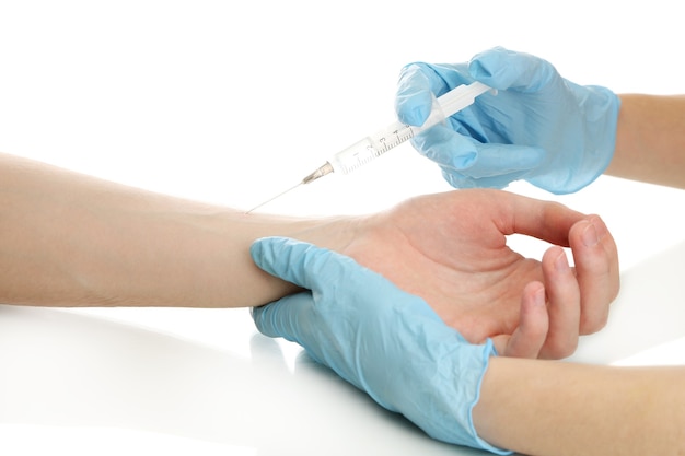 Dokter spuit met een vaccin in de hand van de patiënt, op wit te houden