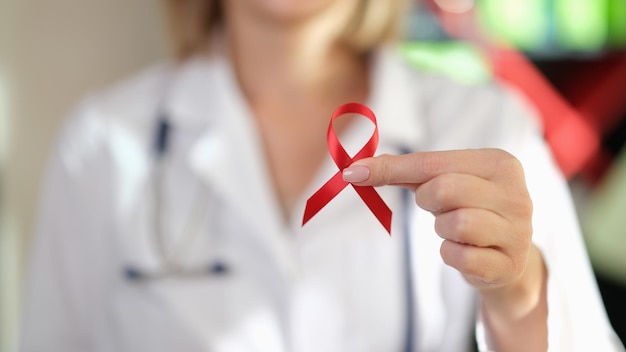 Dokter toont rood lint als symbool van wereld aids dag internationale wereld aids dag bewustzijn