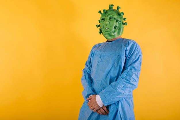 Foto dokter verpleegster draagt een pbm vermomd als coronavirus met latex masker covid virus met gekruiste armen op gele achtergrond coronavirus concept