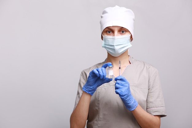 Dokter, verpleegster in medisch masker en handschoenen met griep, mazelen, coronavirus, covid-19 vaccinziekte die zich voorbereidt op vaccinatieschot voor klinische proeven bij mensen
