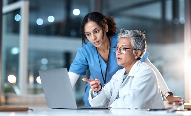 Dokter verpleegster of laptop in nachtelijke gezondheidszorg planning onderzoek of chirurgie teamwerk in wellness ziekenhuis Pratend denken of medische vrouwen over technologie voor samenwerkingshulp of app voor levensverzekeringen