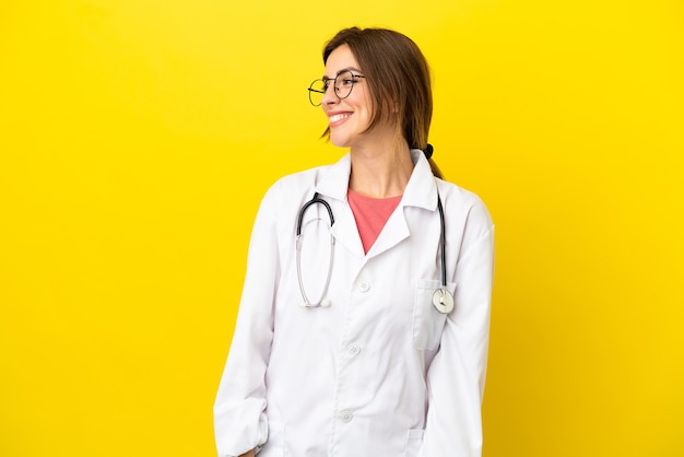 Dokter vrouw geïsoleerd op gele achtergrond op zoek naar kant