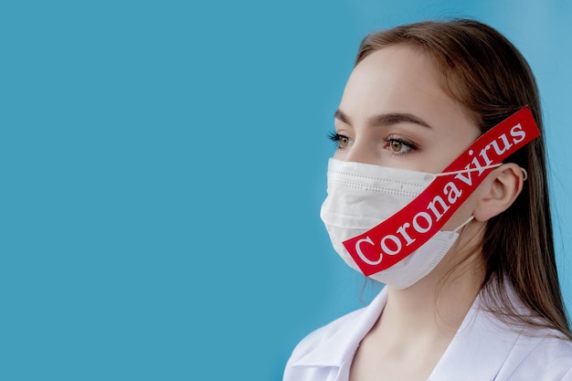 Dokter vrouw met chirurgisch masker wijzend naar rood papier met bericht Coronavirus op blauwe achtergrond Wereldgezondheidsorganisatie WHO introduceerde nieuwe officiële naam voor de ziekte van Coronavirus genaamd COVID19