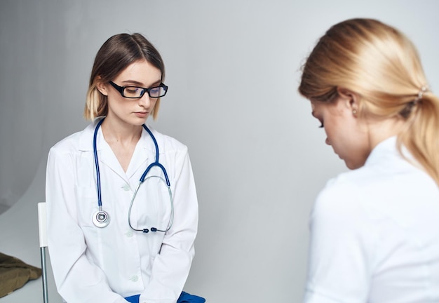 Dokter zit op een stoel en een vrouwelijke patiënt binnen op een lichte achtergrond Hoogwaardige foto