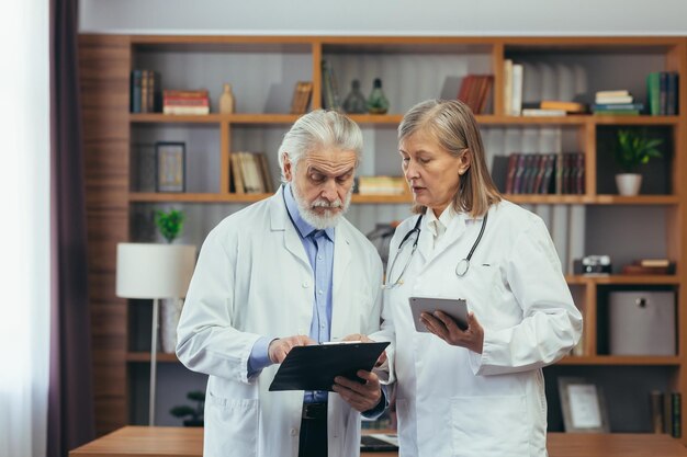 Dokterscollega's van een persoon en een vrouw met grijs haar zijn artsen die in een klassiek medisch kantoor van een kliniek oefenen
