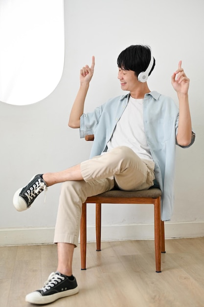 Dolblije jonge Aziatische man die geniet van de muziek die naar muziek luistert via een koptelefoon