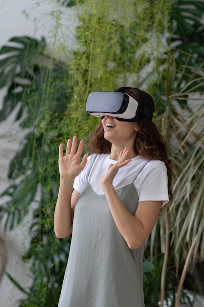 Dolblije jonge vrouw die vrije tijd doorbrengt in virtual reality terwijl ze ontspant in de eigen tuin