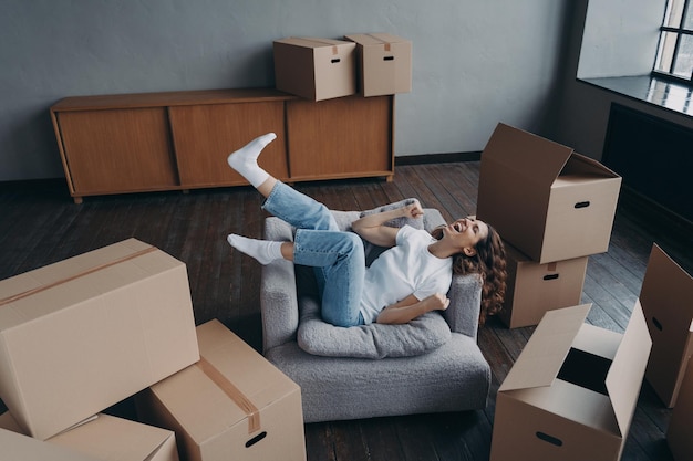 Dolblije spaanse jonge vrouw heeft een nieuw appartement gekocht Lady ontspant in fauteuil