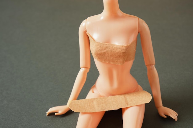 Doll body and adhesive plaster on dark green background