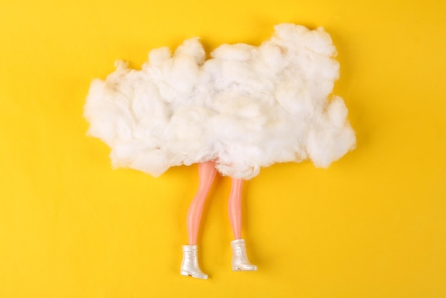 Doll legs behind the clouds on yellow background Minimalism