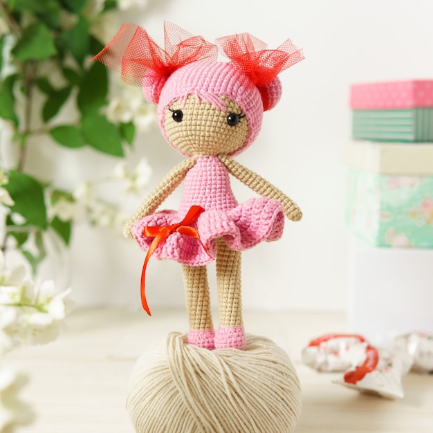 Photo a doll made of wool thread. handmade knitted stuffed toy on a wooden table.