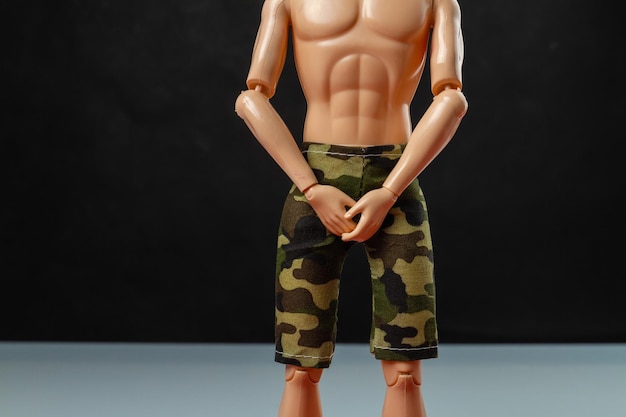 Doll man with military shorts and naked torso mannequin on black background