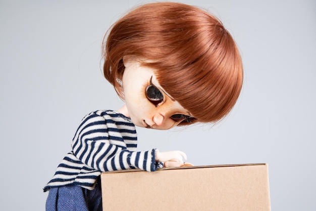 Doll red hairs in jeans with brown carton box moving crate pretty fashion girl