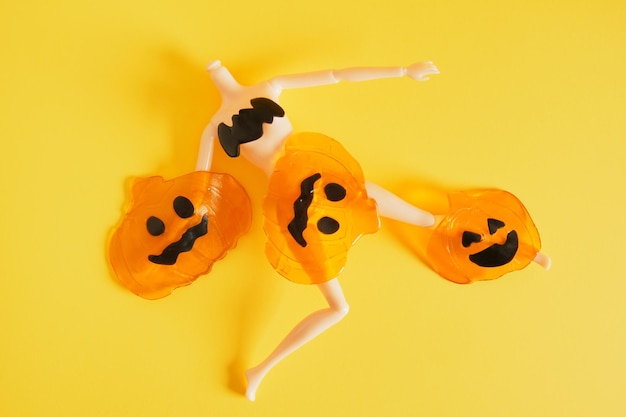 Doll and silicone pumpkins on yellow background