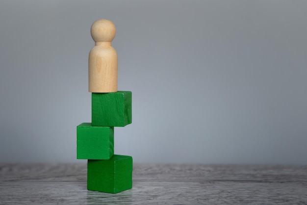 Doll standing on top of unstable wooden block on table Risk uncertainty and challenge concept