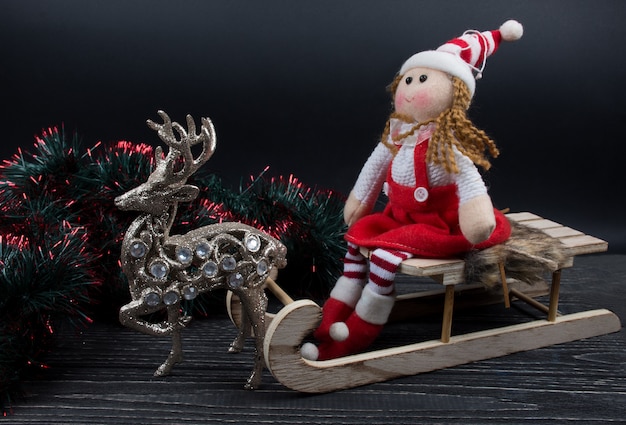 Doll on a wooden Christmas sleigh and a toy reindeer