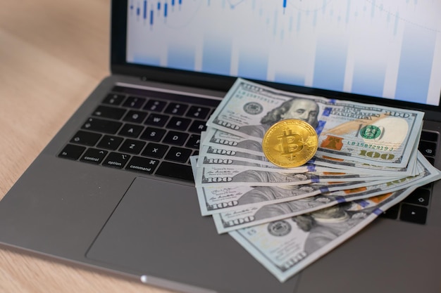 Dollar bills and bitcoin on a background laptop with charts Bitcoins growth chart