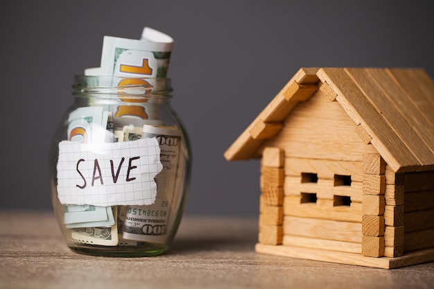 Dollar bills in glass jar and text save on wooden table