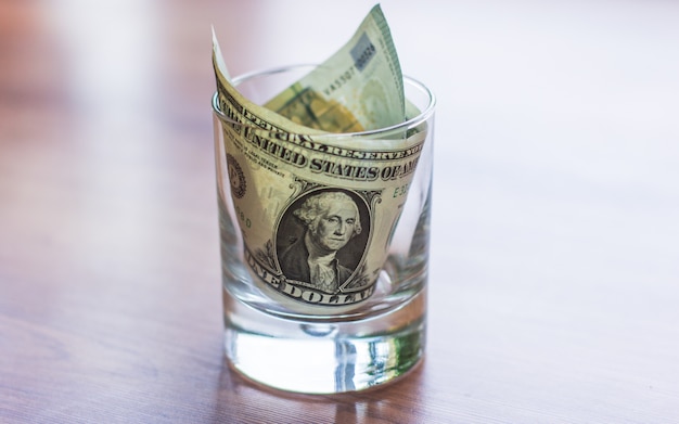 Dollar bills in glass jar on wooden table. Saving money concept